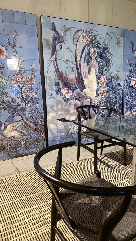 Blue and purple, decorative, tiled screens depicting birds and flowers are used as wall art in a modern dining room setting.