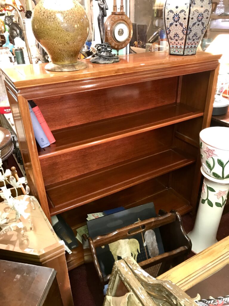 A glossy, Chinese-style wooden bookshelf in a secondhand furniture shop.