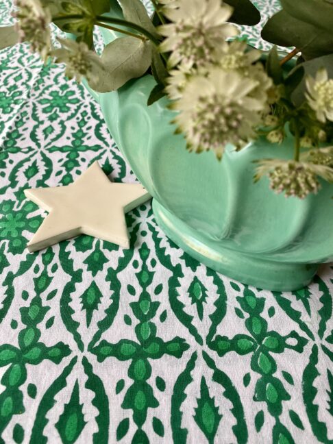 Detail of a pretty, block printed tablecloth styled with a retro vase and white Christmas star decoration.