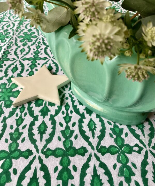 Detail of a pretty, block printed tablecloth styled with a retro vase and white Christmas star decoration.