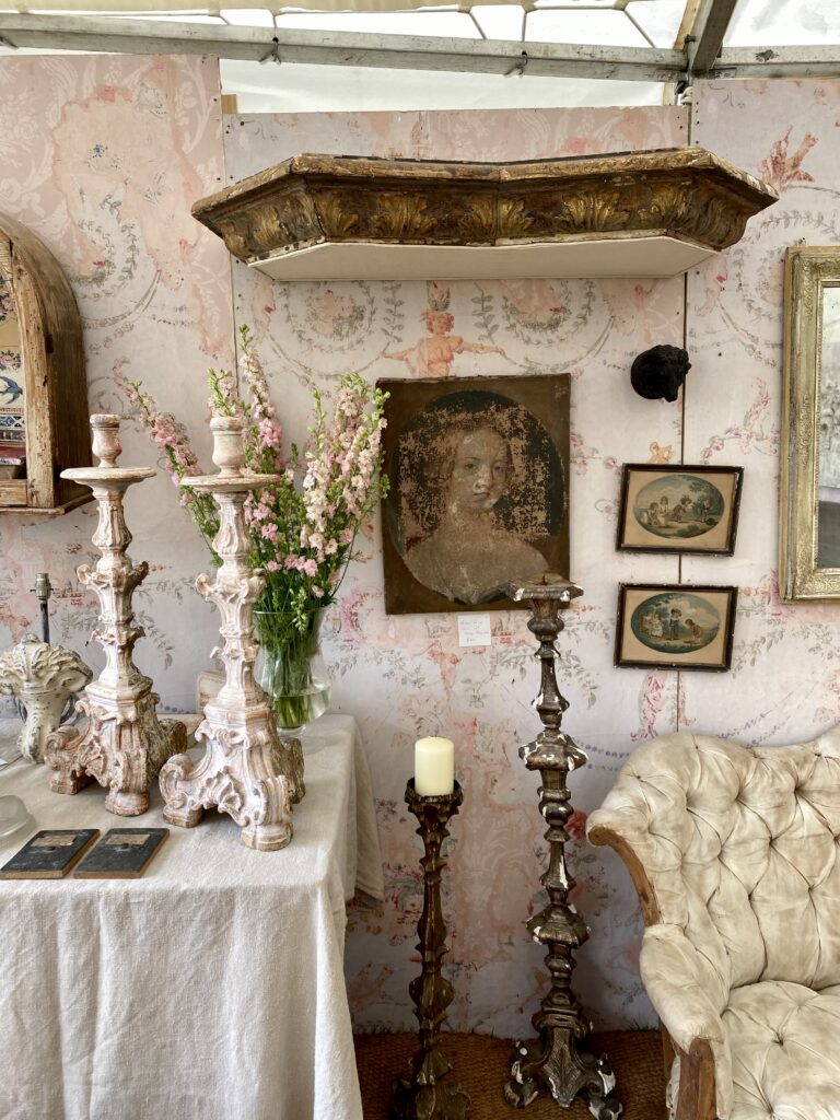 A selection of Italian and French antique candlesticks and decorative finds at an antiques fair.