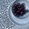 Black and white block print cotton tablecloth with a bowl of cherries.