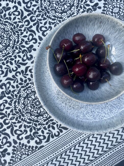 Black and white block print cotton tablecloth with a bowl of cherries.