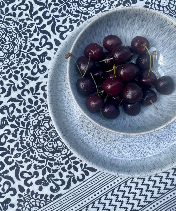 Black and white block print cotton tablecloth with a bowl of cherries.
