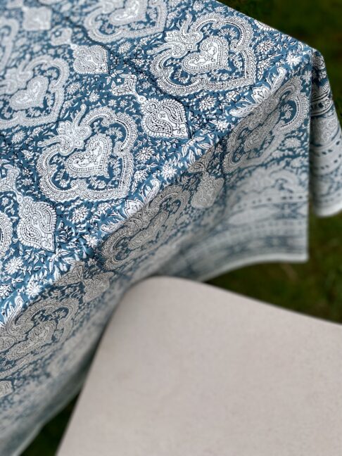 A modern outdoor chair with a pretty, Indian-style printed tablecloth.