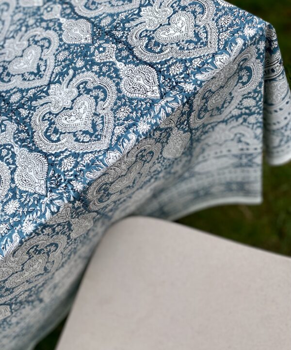 A modern outdoor chair with a pretty, Indian-style printed tablecloth.