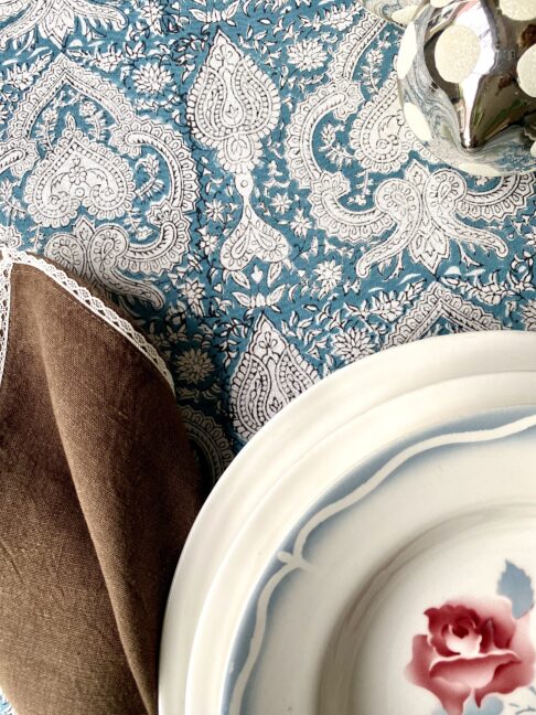 Blue Mughal patterned tablecloth detail on a festive table.