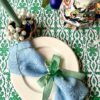 Green patterned tablecloth in Indian block print on a festive table setting.