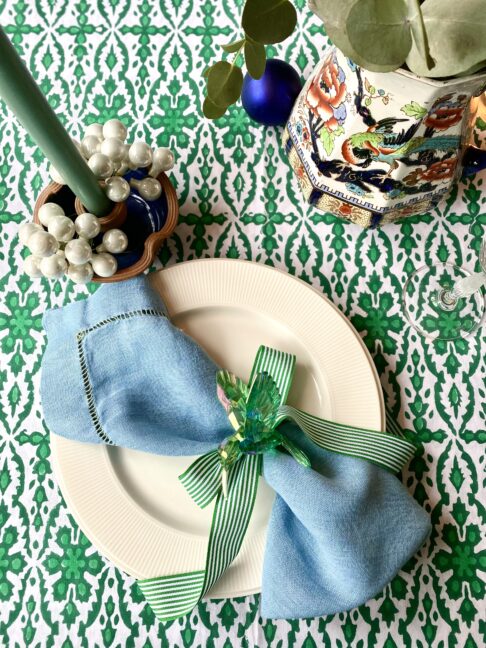 Green patterned tablecloth in Indian block print on a festive table setting.