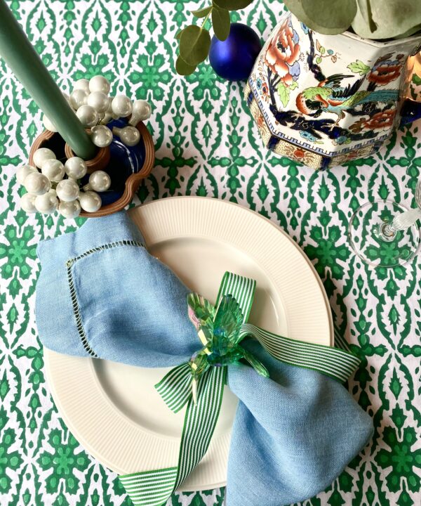 Green patterned tablecloth in Indian block print on a festive table setting.