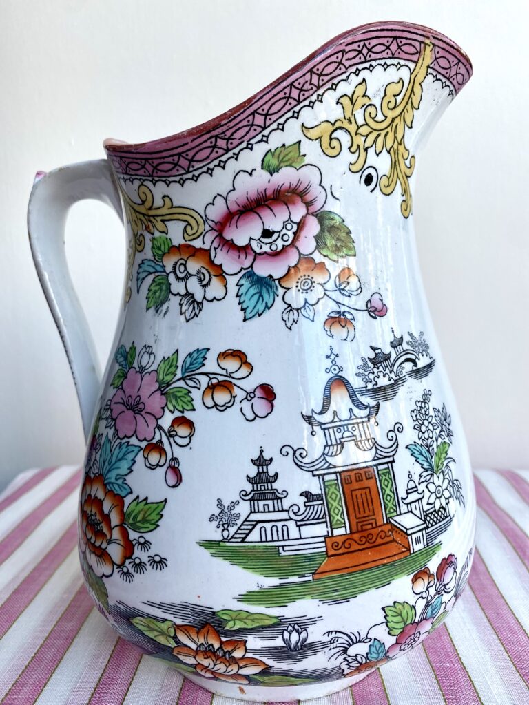 A pretty pink, green, yellow, and orange vintage jug depicting an Asian temple scene.