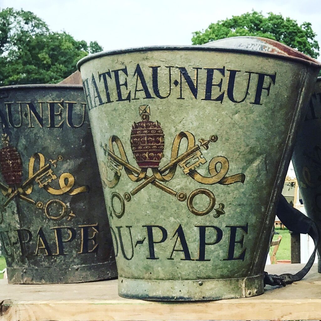 Vintage, metal, grape-harvesting buckets depicting the name of the domaine: Chateau Neuf Du Pape.