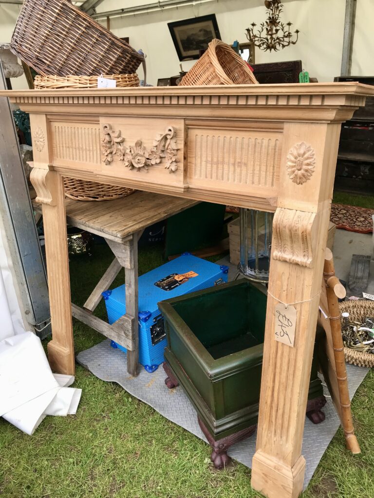 A traditional carved and fluted wooden mantlepiece at an antiques fair.