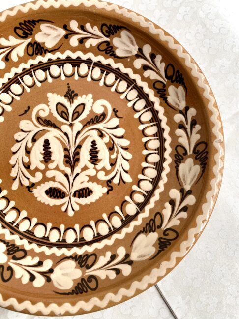 A rustic, Hungarian pottery plate for display in browns, creams and terracotta hues.