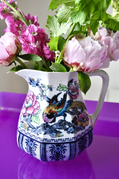 Vintage jugs for flowers. Losolware 'Shanghai' jug filled with roses and peonies on a purple Perspex side table.