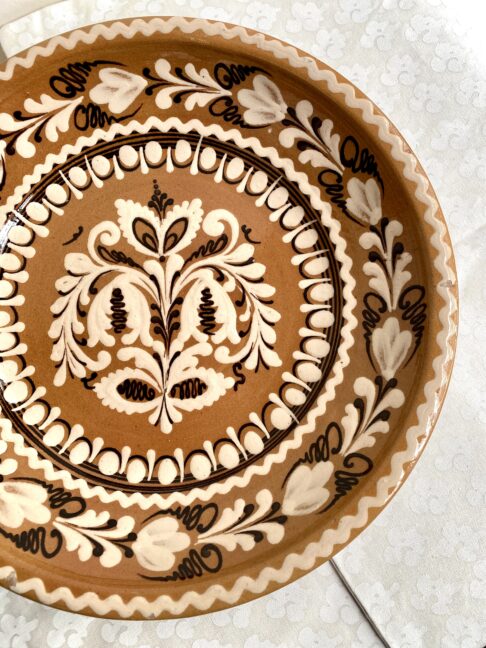 A vintage, decorative wall plate from a Hungarian pottery in earthy browns, creams and terracotta.