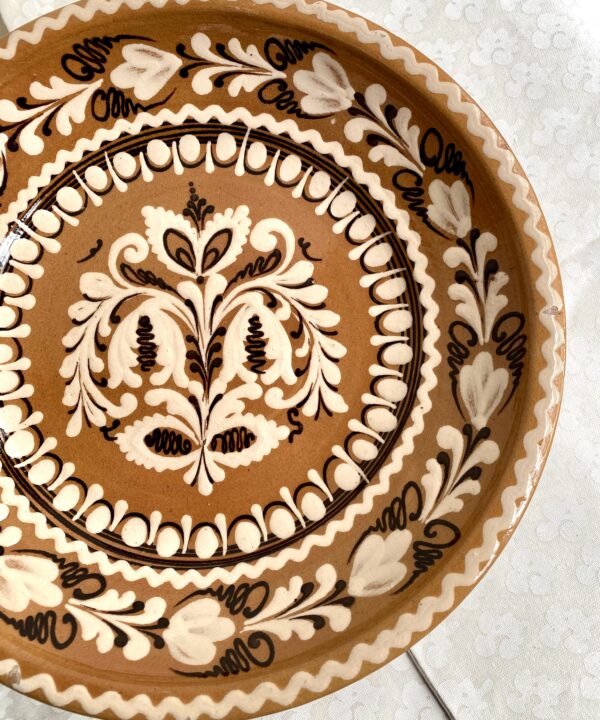 A vintage, decorative wall plate from a Hungarian pottery in earthy browns, creams and terracotta.