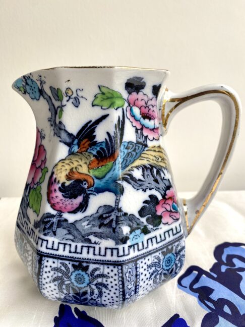 A vintage jug with a Chinese-style design depicting a colourful bird in pretty pink, blue, green and yellow.