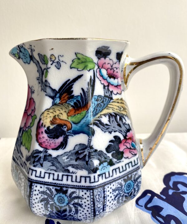 A vintage jug with a Chinese-style design depicting a colourful bird in pretty pink, blue, green and yellow.