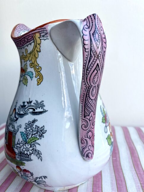 The decorative handle on a vintage, pink, Chinese-flloral jug.