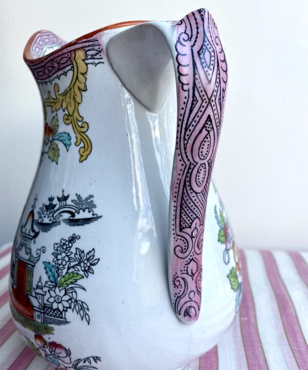 The decorative handle on a vintage, pink, Chinese-flloral jug.