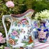 A vintage floral jug in pink and orange with Chinese-inspired motifs in an outdoor setting.