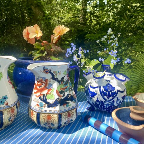 An outdoor table setting with blue and white crockery and vintage jugs for flowers. Seasonal eclectic homewares both vintage and new.