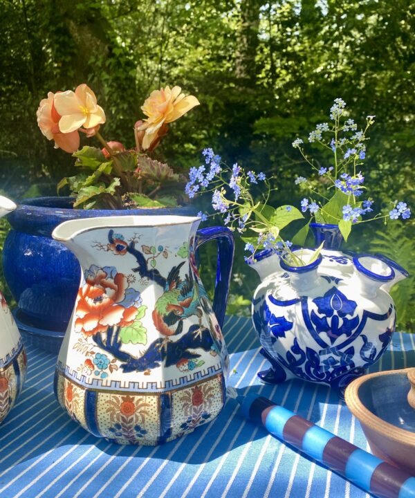 An outdoor table setting with blue and white crockery and vintage jugs for flowers. Seasonal eclectic homewares both vintage and new.