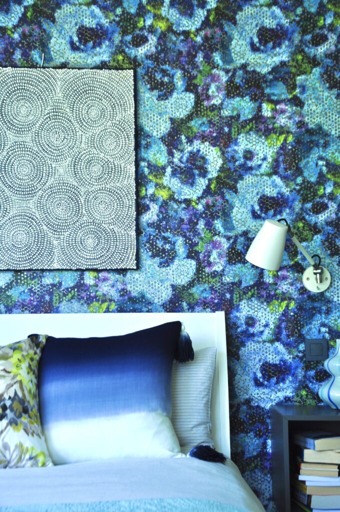 A bedroom vignette featuring a striking blue and green, statement floral wallpaper by Designers Green.