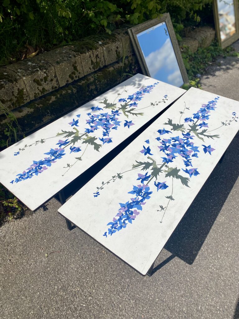 A pair of low, rectangular coffee tables with pretty, blue Delphinium prints.