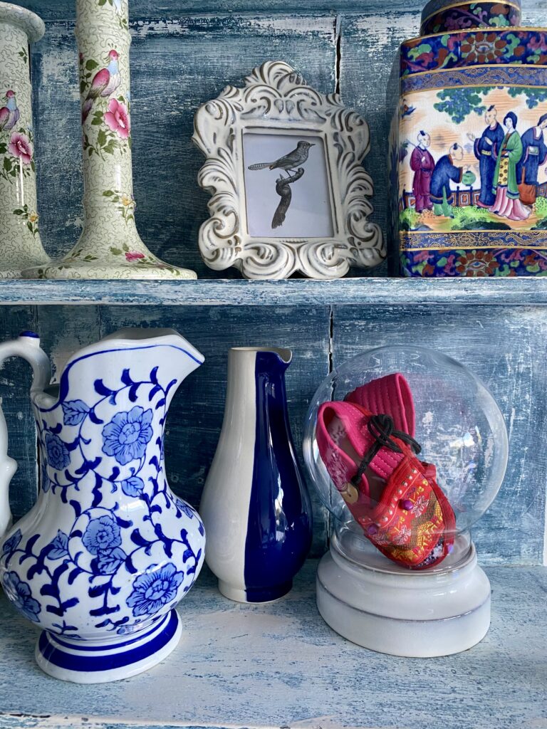 A selection of antique pots, jugs and candlesticks on a vintage, Swedish shelf in blue.