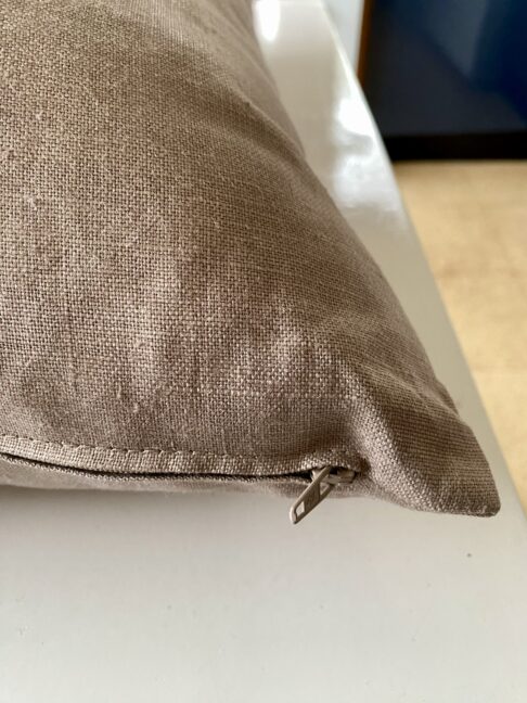 Zip detail on a taupe, glazed and brushed linen cushion.