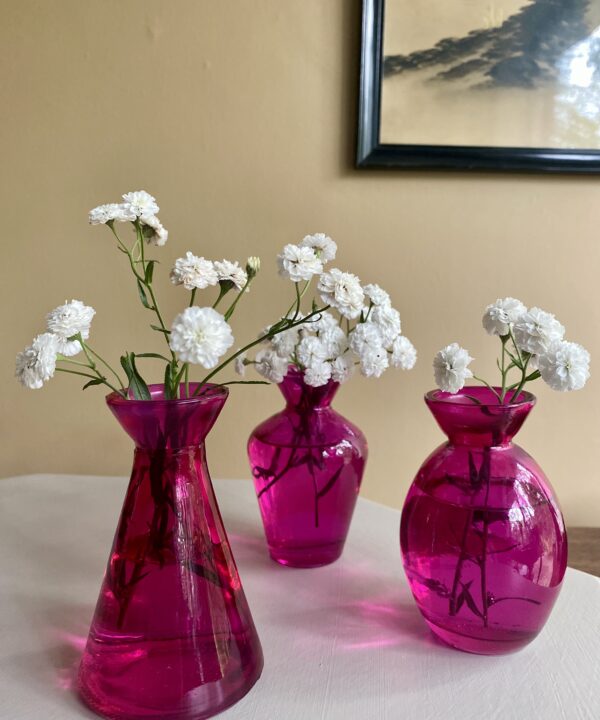 A trio of hot pink glass bud vases.