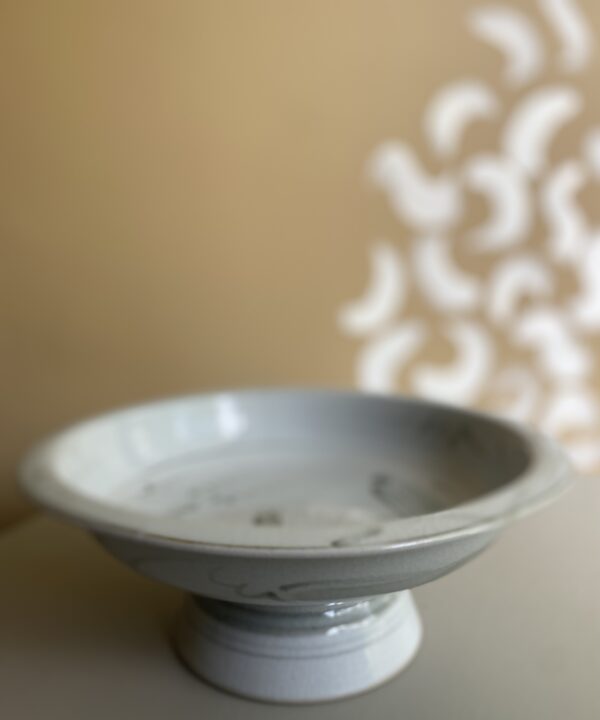 Rustic Thai pottery in off-white in front of a warm beige backdrop.