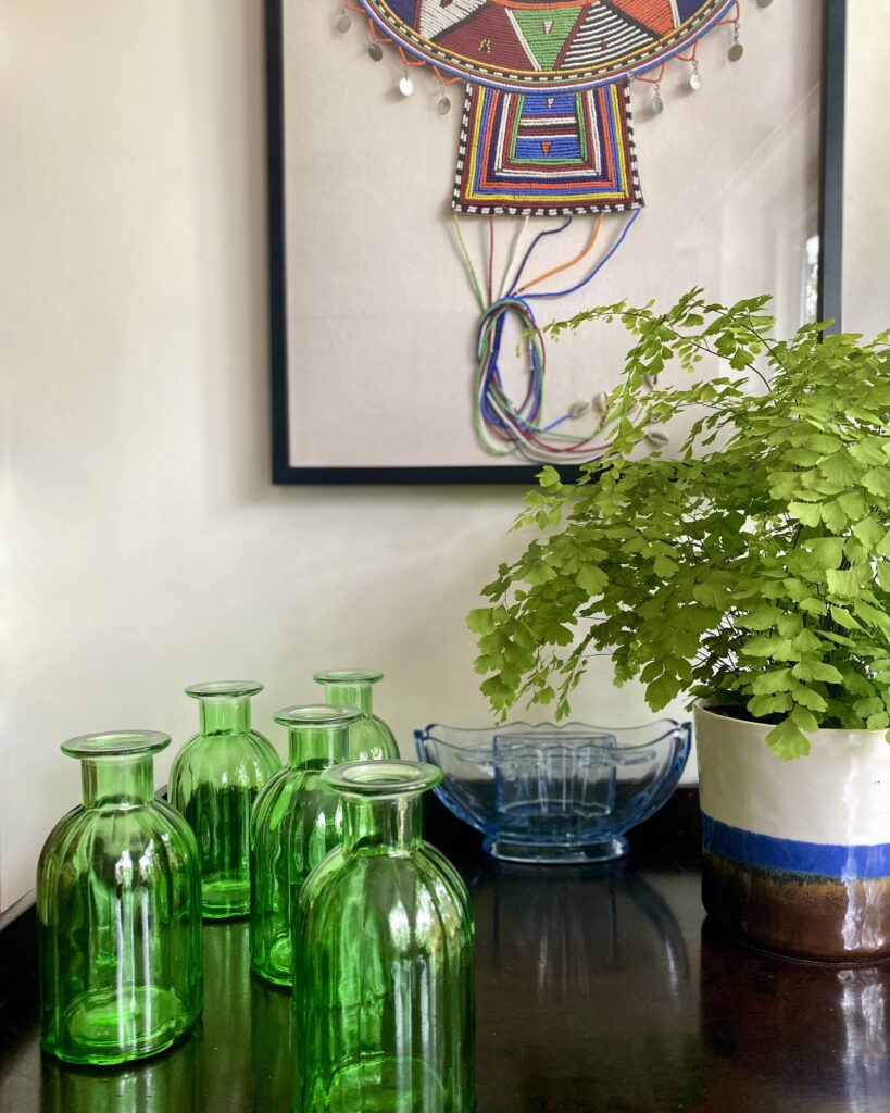 Green bottle glass vases and a potted Maidenhair fern.