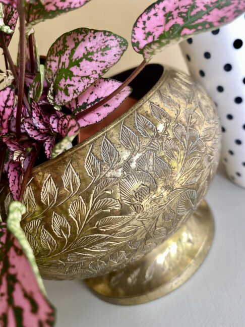 A vintage brass rose bowl or vase with engraved detailing.