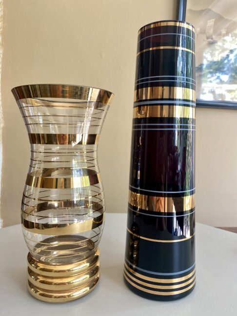 Two retro glass vases; one black, on clear; each with gold banding.