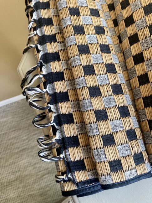 A tasselled table runner in checquer board rattan.