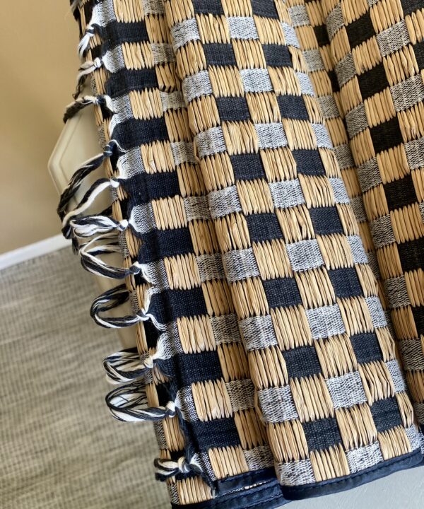 A tasselled table runner in checquer board rattan.