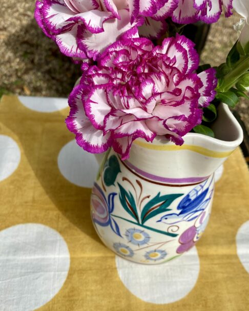 Overhead shot of a Poole pottery jug, filled with pink, variegated carnations.