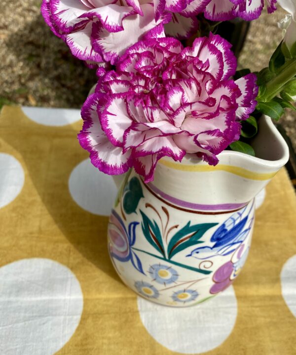 Overhead shot of a Poole pottery jug, filled with pink, variegated carnations.