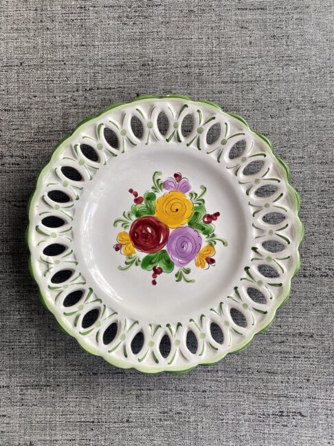 A wall plate with decorative florals hand-painted in bright colours.