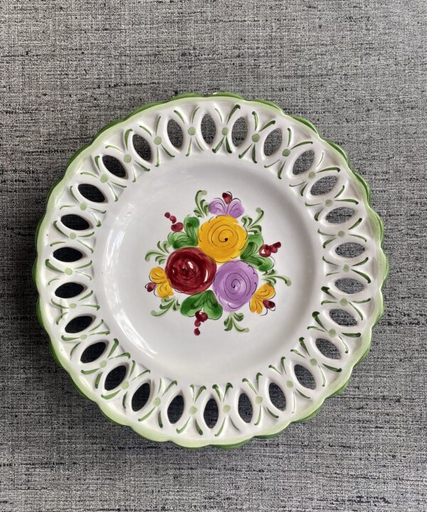 A wall plate with decorative florals hand-painted in bright colours.