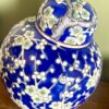 A blue and white china pot with lid. Intense blue background with a pretty, trailing blossom design in white and mint green.