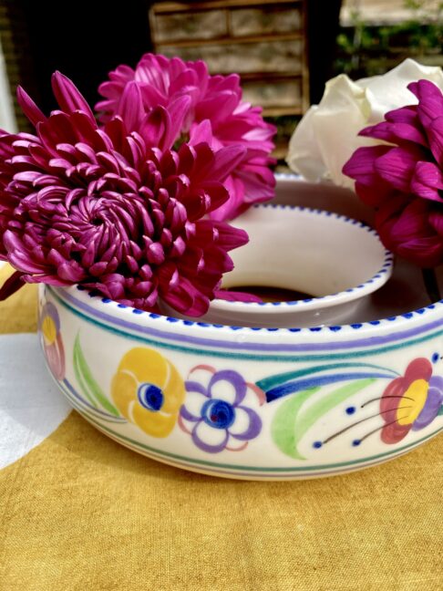 A colourful Poole pottery posy ring filled with pink blooms.