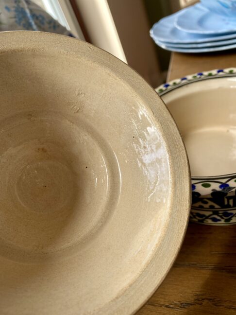 The glazed cream interior of a vintage, ceramic lidded pot.