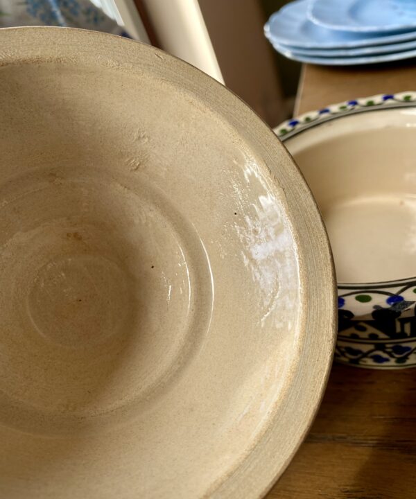 The glazed cream interior of a vintage, ceramic lidded pot.