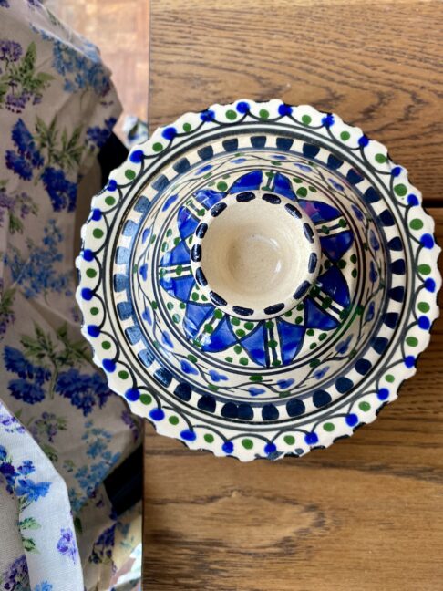 A decorative hand-painted pot with lid on a wooden table.