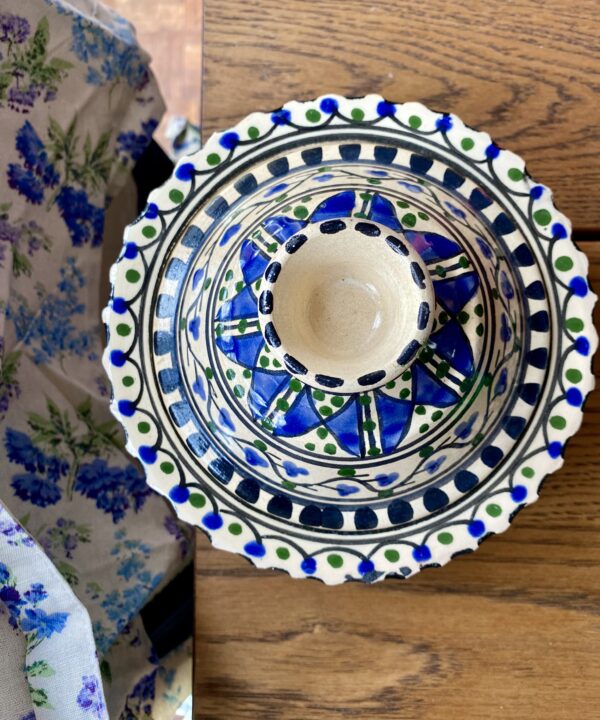 A decorative hand-painted pot with lid on a wooden table.