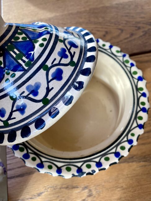 A cream ceramic lidded pot with hand-painted patterning.